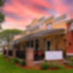 Inviting stone-and-brick diner in River Edge NJ beneath a vibrant sunset sky, with a lush patio surrounded by greenery—reflecting the warmth and community feel of Bergen County neighborhoods, ideal for buyers working with The Gill Group, trusted real estate professionals.