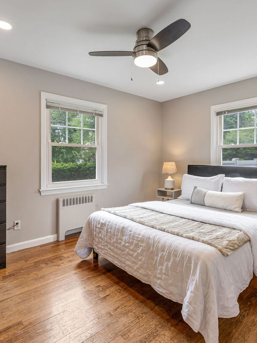 Primary bedroom with hardwood floors natural light and neutral decor in Bergen County home for sale