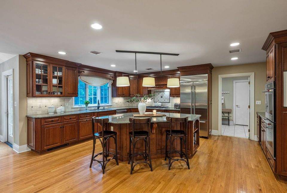 Gourmet kitchen with cherry cabinets, granite countertops, center island, and premium appliances in Allendale NJ home.