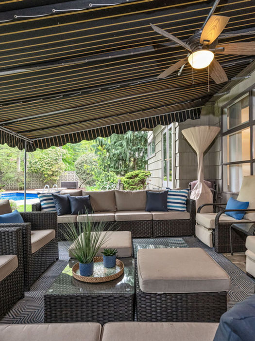 Covered outdoor patio lounge with comfortable seating and backyard views at luxury Hillsdale NJ property.