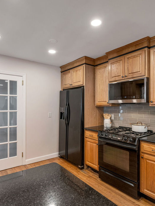 Eat-in kitchen with wood cabinets stainless appliances and sliding door access to covered deck in Ramsey NJ home