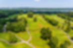 Aerial view of a scenic golf course in River Vale, NJ, with manicured fairways, sand traps, and a distant lake—highlighting the town’s upscale amenities and natural beauty, with The Gill Group as leading real estate agents in River Vale and greater Bergen County.