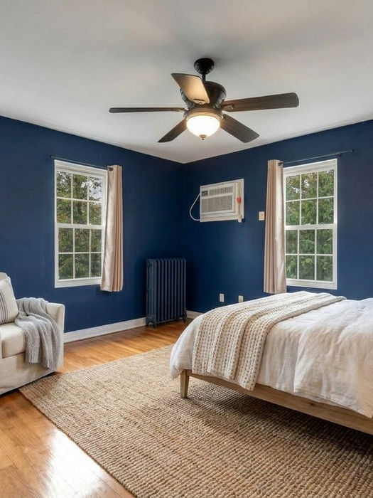 Virtually staged navy bedroom with a bed and armchair at 713 Lincoln Avenue, Ridgefield Park, NJ