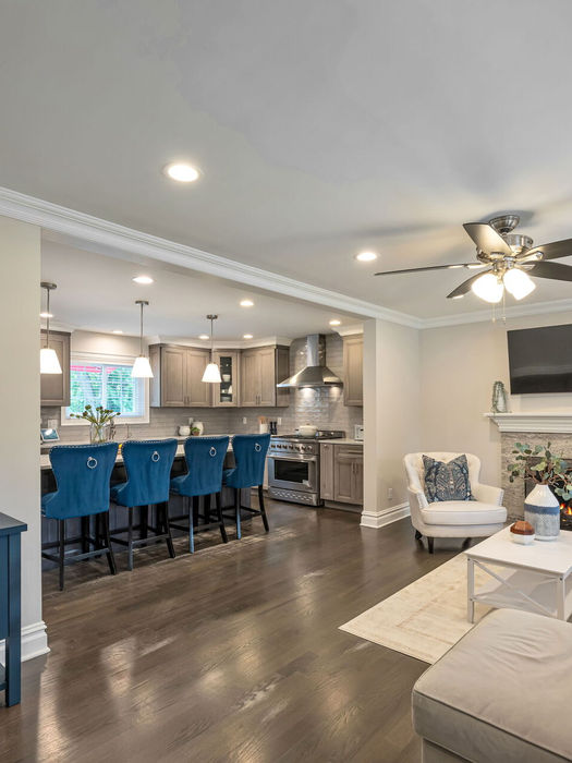 Open-concept living room and dining area with gas fireplace, hardwood floors, and natural light in a luxury home for sale in Glen Rock NJ.