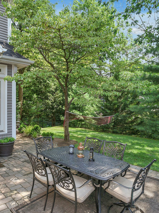 Private backyard patio surrounded by mature trees and babbling brook at Glen Rock NJ rental home