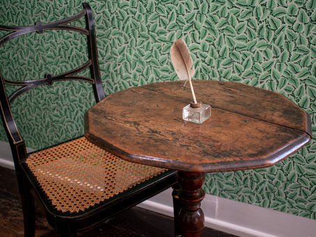 Jane Austen's writing table in Chawton, with quill pen and chair. Photo courtesy of Jane Austen's House.