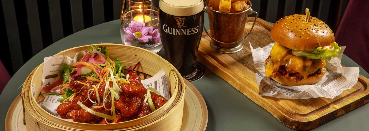 Table with food, GUINNESS pint, chicken, burger, fries for dinner.