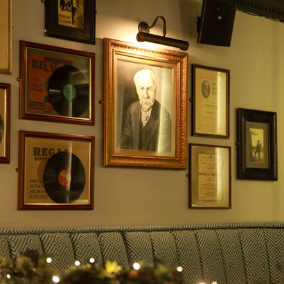 Cozy wall with framed portrait, 'REGAL' records, and various art.