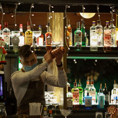 Bartender shaking a cocktail behind a fully stocked bar.
