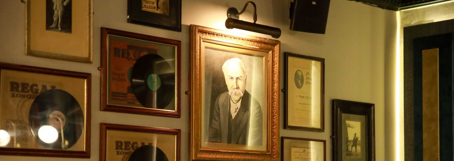 Wall decorated with framed "REGAL" records and old man portrait, cozy interior lighting.