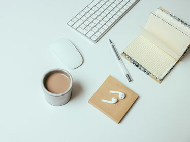 A notebook and a cup of coffee on a clean, white desk