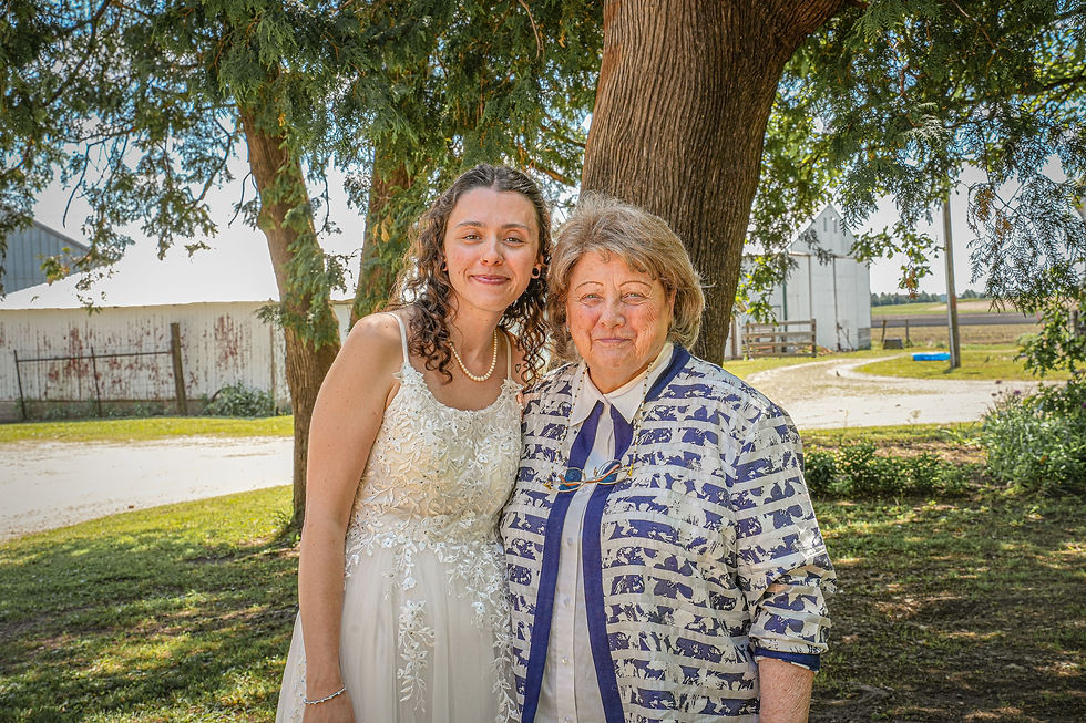 A bride and her grandmother pose in front of a tree.