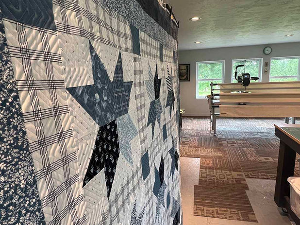 A blue and white hanging up in a sewing room, with 8-point star and plaid patterns