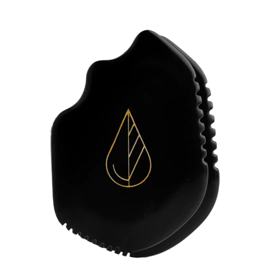 irregularly shaped gua sha tool of black stone with leaf imprint on top.