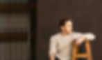 Aussie Actor Rowan Witt, in a retro cream knitted jumper, relaxes on a photography set with a wooden backdrop, at the Sydney Theatre Wharf