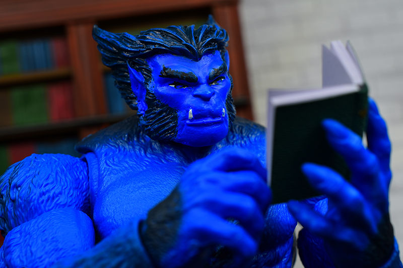 Beast looking curiously at a book in his left hand