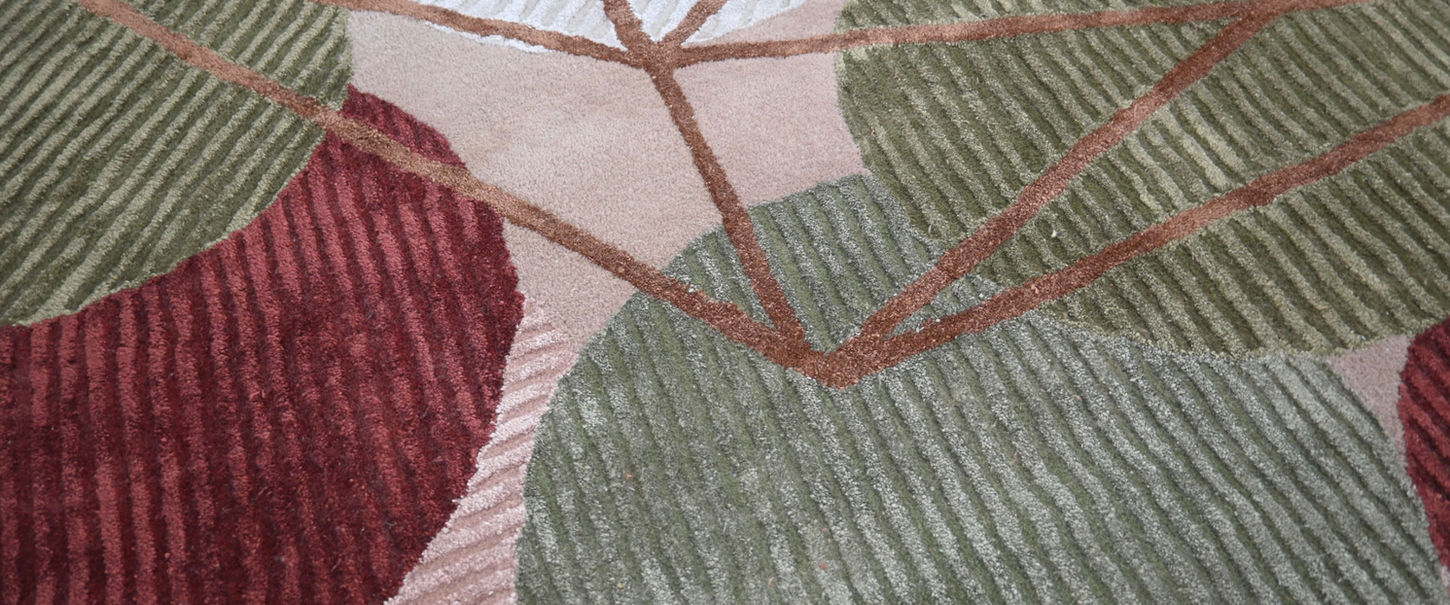 Close-up of the Orbit rug’s textured striped circles in maroon, sage green and blush pink, crossed by copper lines.