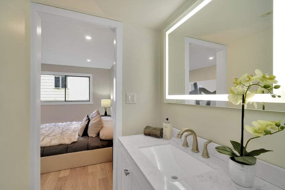 The bathroom boasts a white porcelain sink, a white toilet, and a colorful abstract painting on the wall.