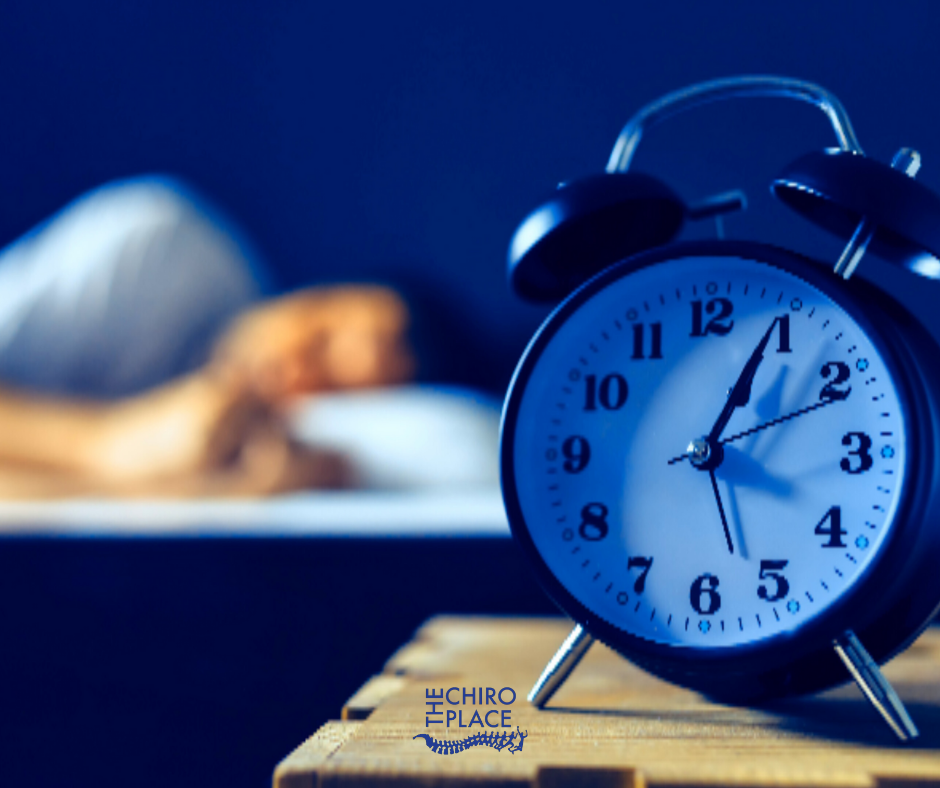 Clock on desk and someone alseep behind it