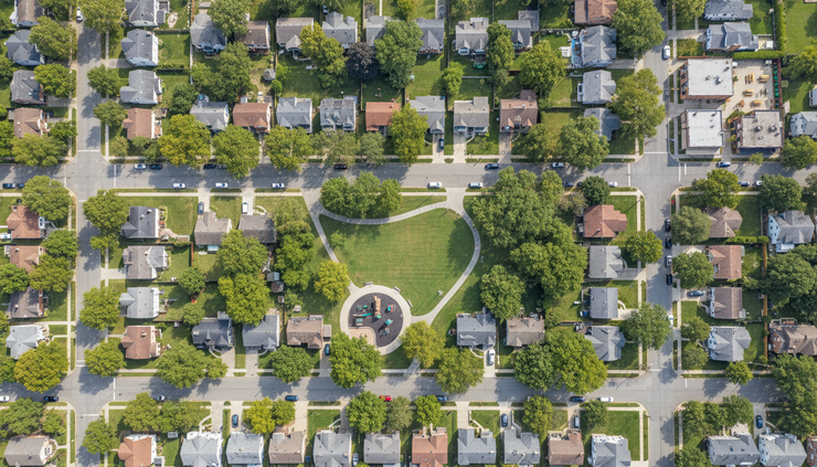 Aerial view of a residential neighborhood with homes, trees, a park, and shops nearby.