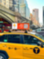 Eye-level view of a yellow hybrid taxi on a city street