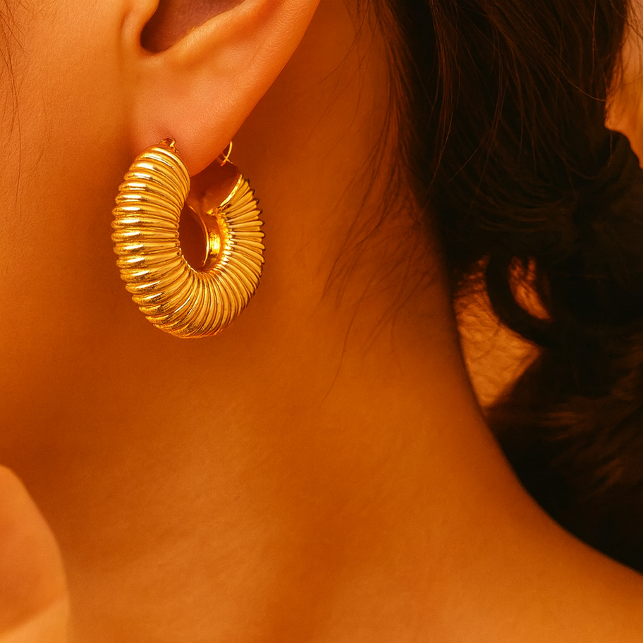 Gros plan d'une boucle d'oreille dorée avec Boucles d’Oreilles Hammer Shine – Créoles Motif Martelé et Zircon Maison Argÿel