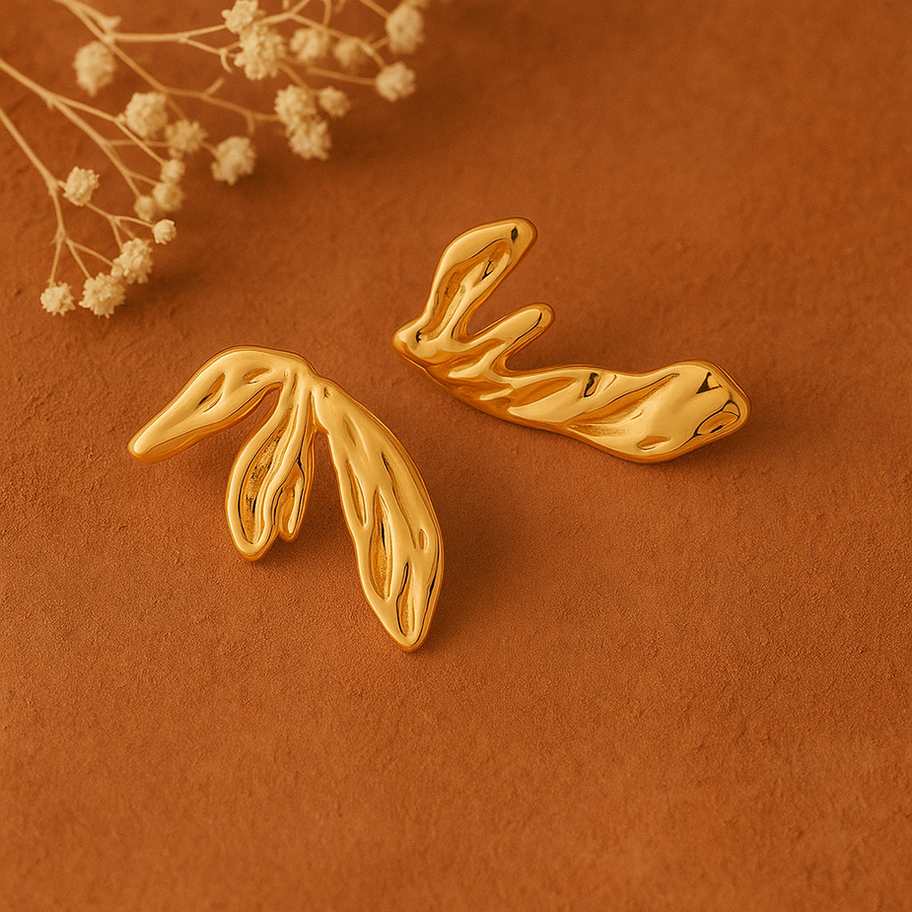 Boucles d'oreilles dorées en forme de feuilles sur fond marron, Maison Argÿel.
