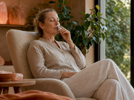 En kvinde sidder og får inhalationsbehandling med salt, hvor hun trækker vejret ind i et særligt rum for at styrke sine luftveje.