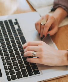 Someone types on the black keyboard a silver aluminium laptop.