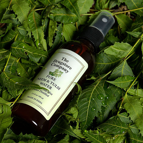Herbal cosmetic spray bottle photographed on fresh neem leaves for skincare portfolio