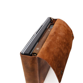 Styled product shot of a distressed leather tablet or e-reader case with a snap closure, showing the device inserted to demonstrate fit and function.
