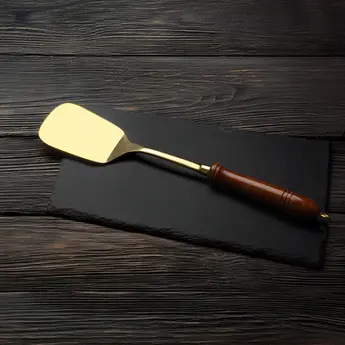 A flat, wide brass spatula (palta) used for flipping, turning, and serving food on a griddle or pan.