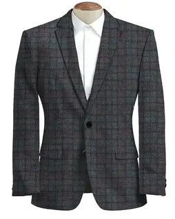 A full-length photograph of a men's tweed blazer hanging on a rustic, handcrafted wooden hanger, showcasing the sophisticated tailoring and overall silhouette of the garment