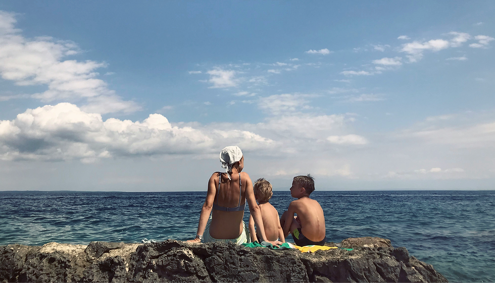 family sitting on a rock by the sea