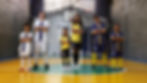 Grupo de estudantes em quadra esportiva, vestindo uniformes de diferentes modalidades, com os braços cruzados.
