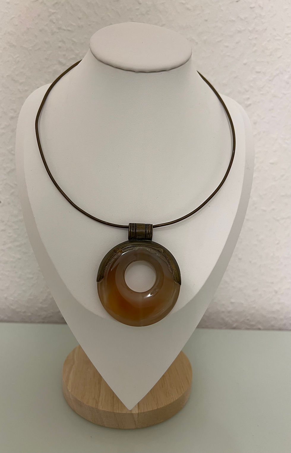 Brown agate circle pendant on metal cord, front view.