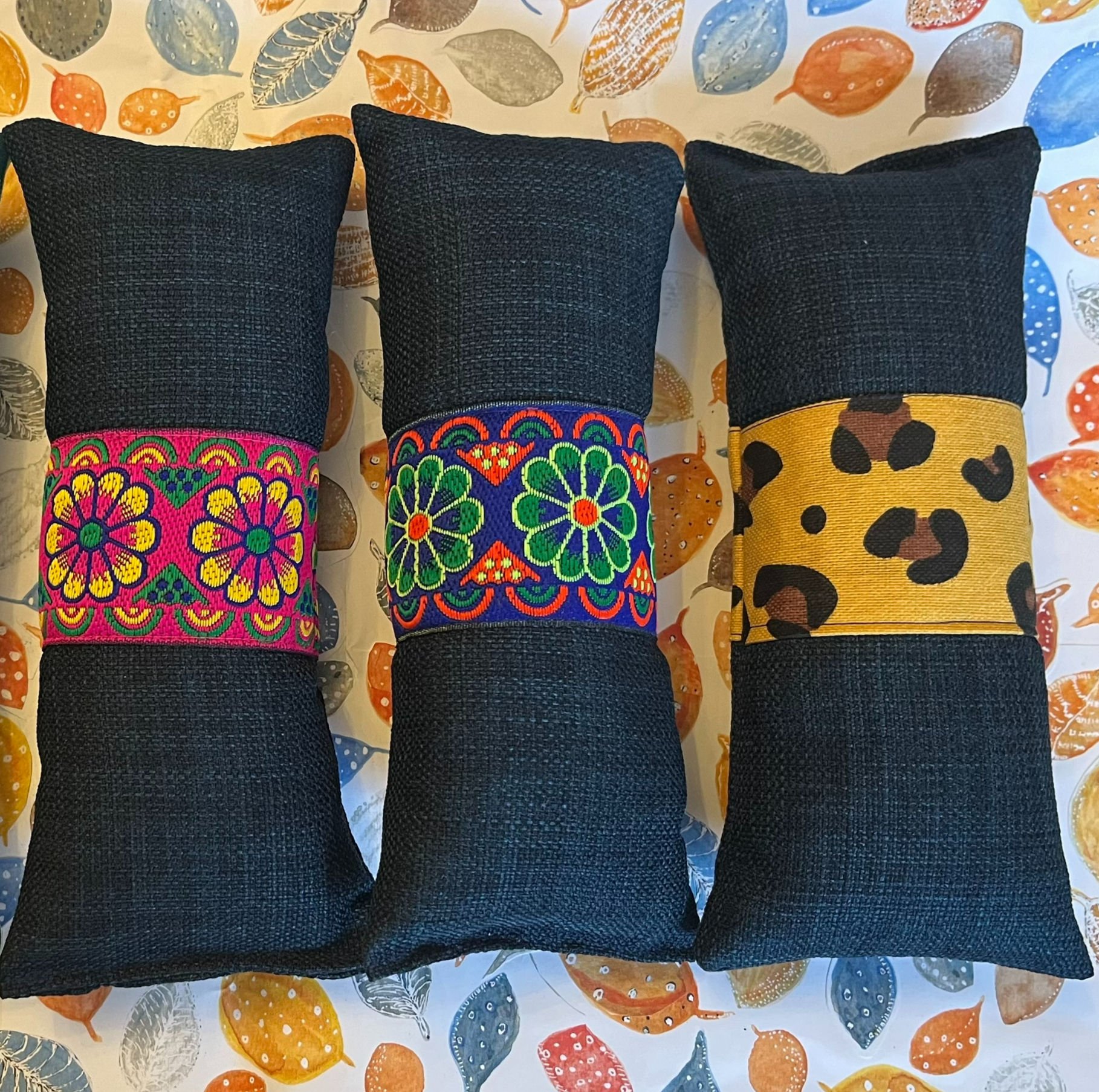 Three dark pillows with colorful patterned bands, home decor background.