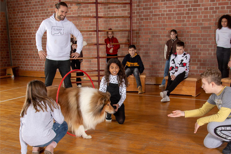 Shooty wird im Kinderseminar rund um den Hund in München durch einen Reifen gelotst 