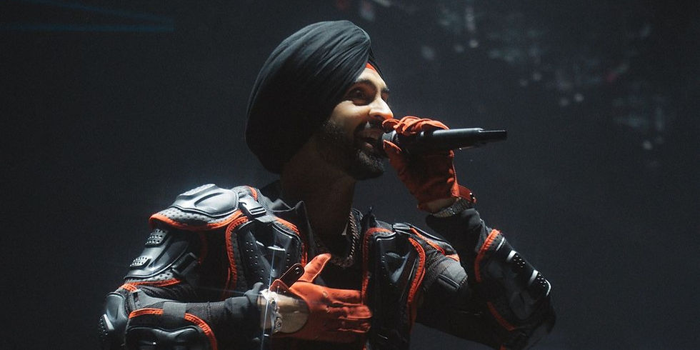 Diljit Dosanjh performing on stage in a black and red attire