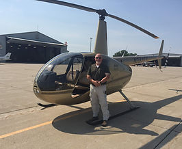 Chris Heckle next to a Robinson helicopter