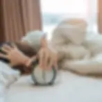 Alarm clock and asian woman hand stop time in bed while sleeping young adult fem