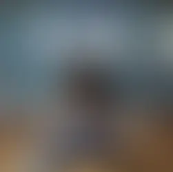 Child in plaid shirt sits at a desk in a classroom. "ADHD" is written on the blackboard with colorful chalk clouds. Classroom setting.