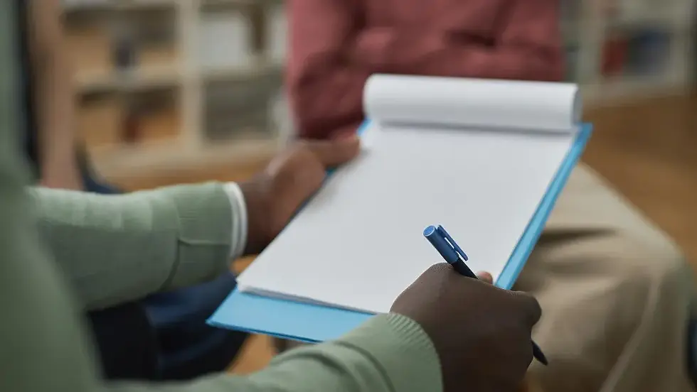 A psychiatrist in Arlington, TX, takes notes during a session to differentiate between panic attacks and anxiety.