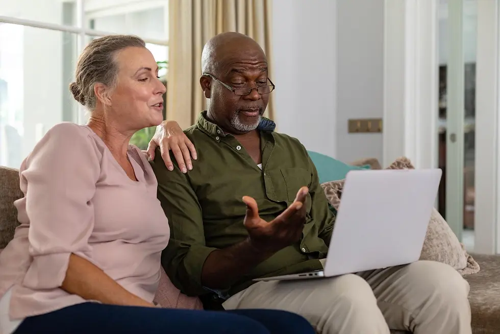 Senior multiracial couple discussing over laptop while sitting on sofa at home. unaltered,