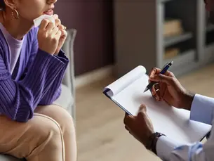 A therapist takes notes during a psychiatric evaluation session, capturing crucial information to develop a personalized treatment plan, highlighting the process from intake to treatment in Columbia, MD.