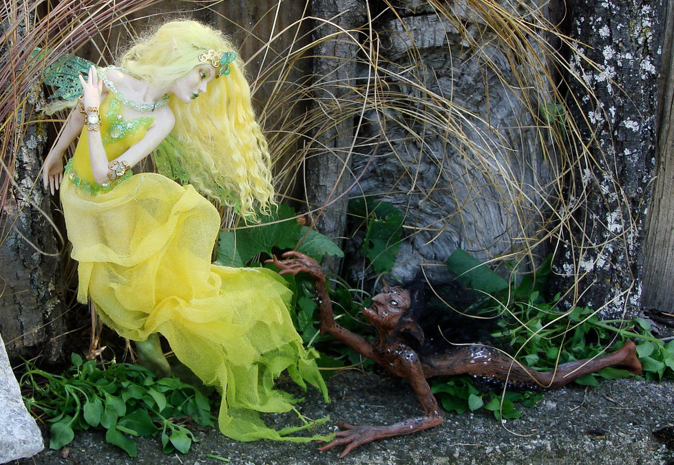 a yellow dressed fae with green wings and blond hair windswept holds her green glass bead necklace posed to fly looking down at a brown goblin wallowing with his hand upraised.