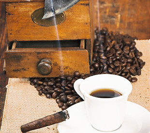 Cup of black coffee and a cigar in the background grinder on a wooden rustic table_edited.