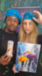 Two people in blue berets hold a painting and a drink can. Vibrant, patterned background. Text: The Artisan. Playful mood.