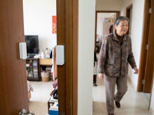 長者一家人在家中一起查看居家安全監察系統的手機應用程式