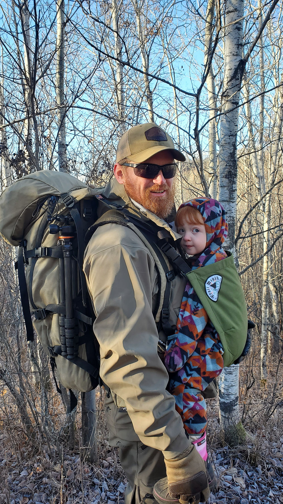 Hunter wearing a Stone Glacier backpack while carrying a child during a winter family hike
